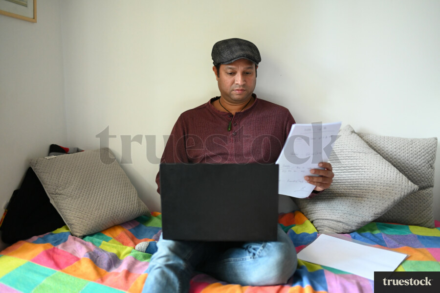 Adult male budgeting finances at home on the bed