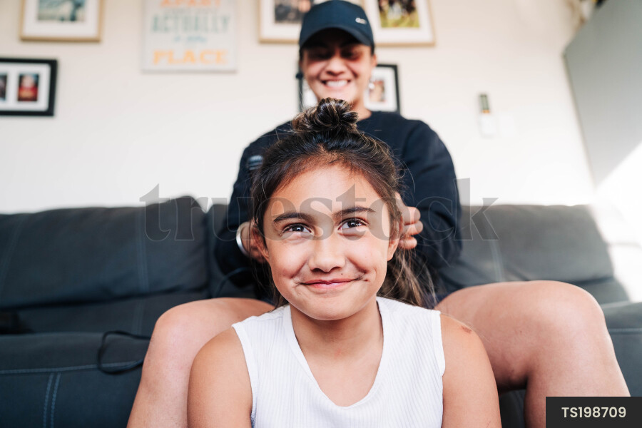 Mother and daughter with hand in hair on sofa in living room