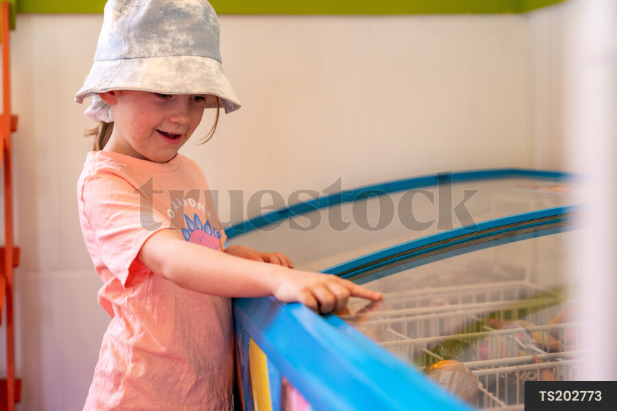 Girl points to ice cream in refrigerator