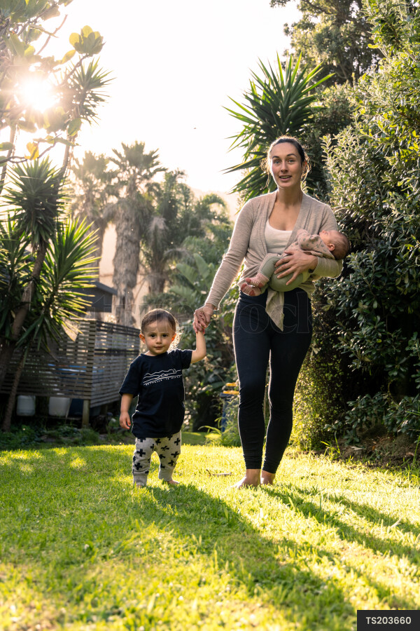 Mother and children holding hands while walking in garden