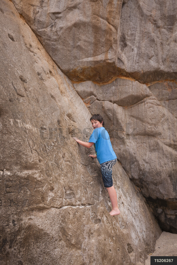 Boy climbing cliff at Whiritoa Beach