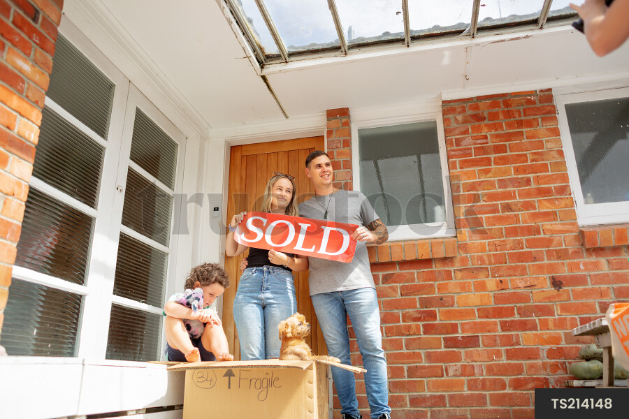 Family with sold sign by house