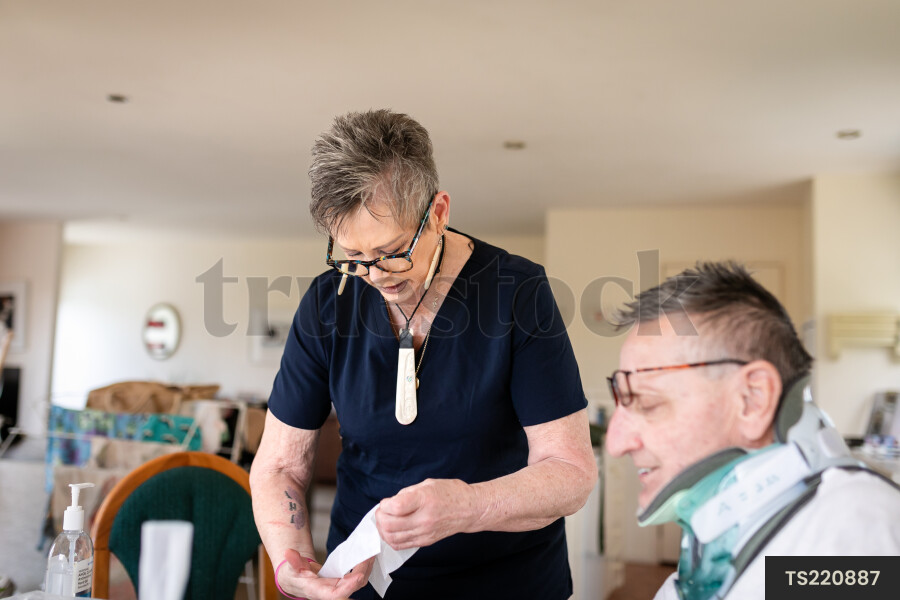 Health carer giving medicine to patient with neck brace