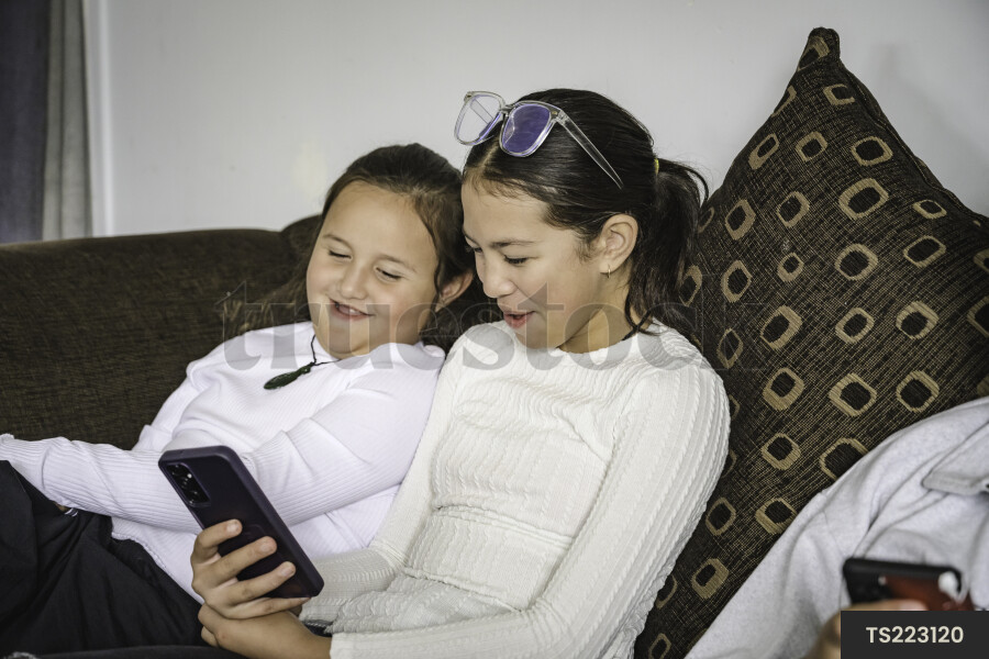 Girls sitting on sofa with smart phone
