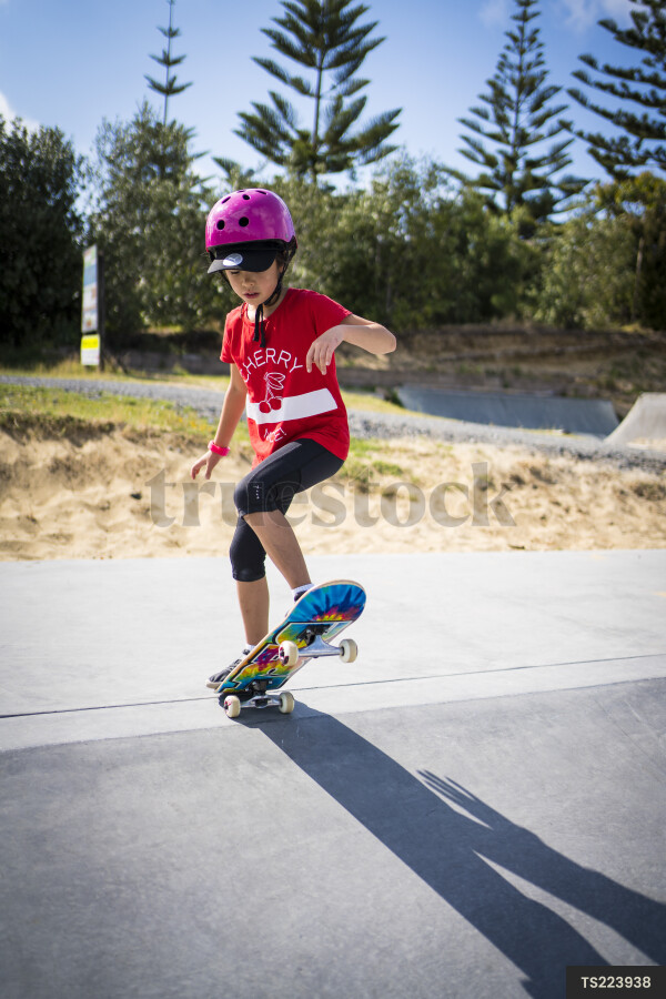 Girl with helmet skateboarding on ramp in park