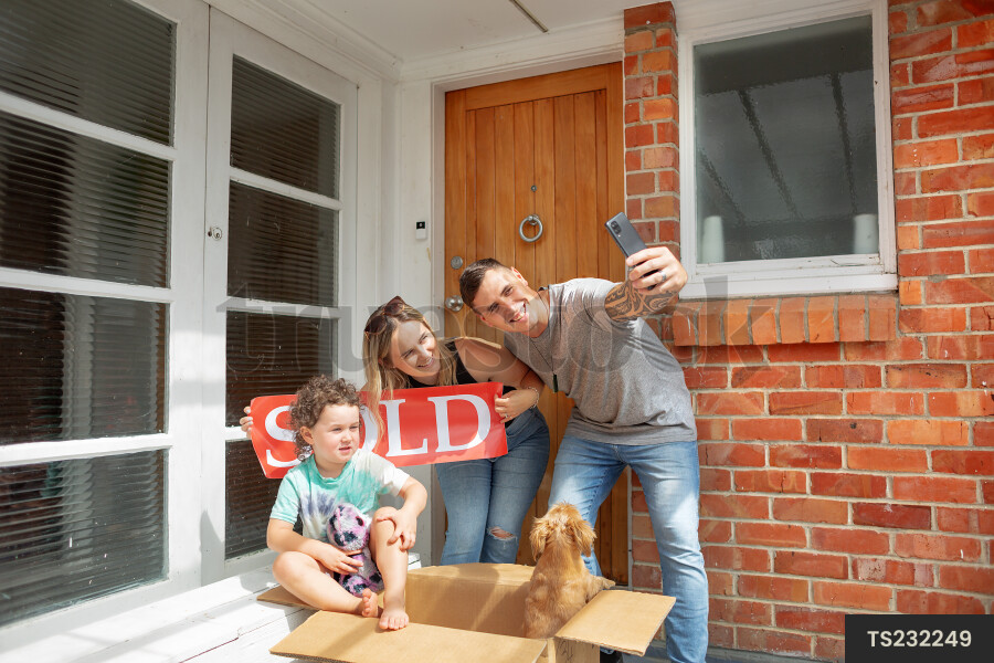 Family with sold sign by house
