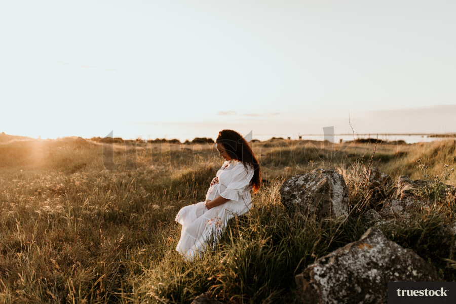 Woman Sitting in Field for Maternity Shoot