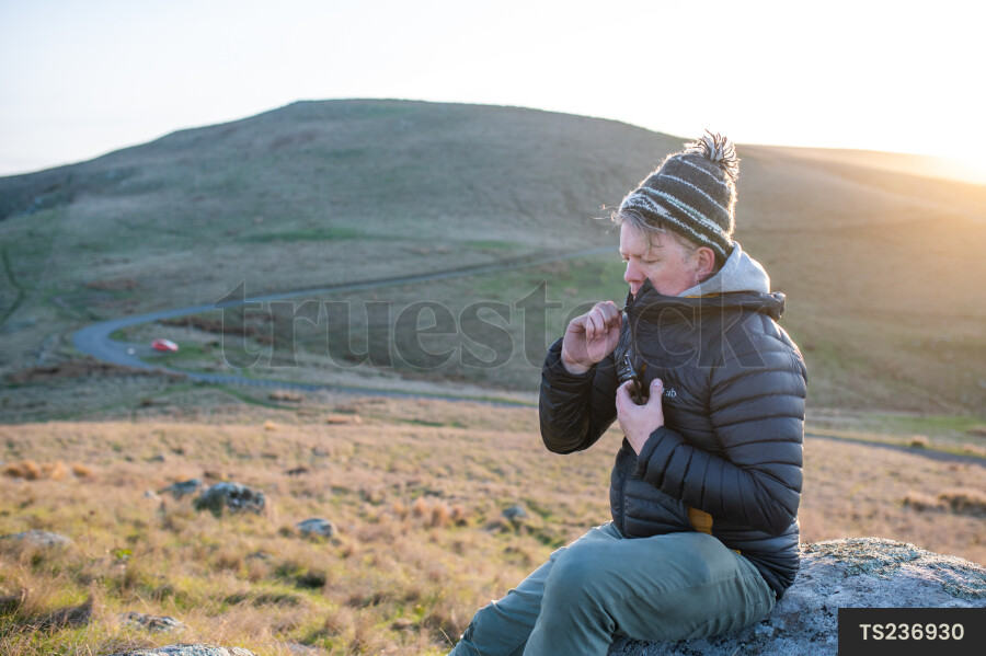 Man sitting on rock on hill