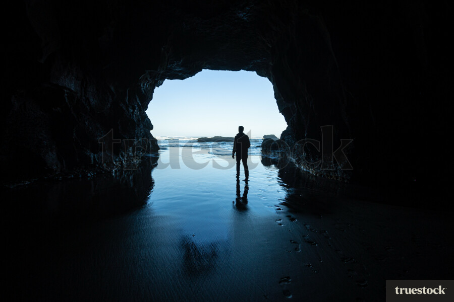 Man Standing in Cave at Beach