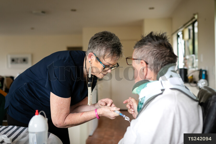 Health carer giving medicine to patient with neck brace
