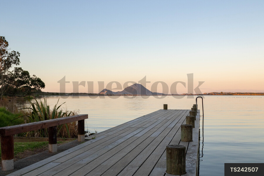 Wood jetty by lake on coastline during sunset