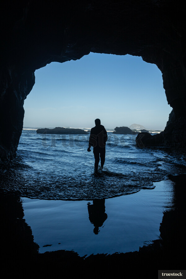Man Standing in Cave at Beach