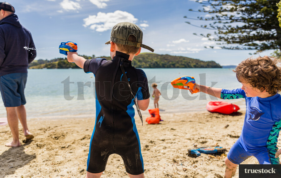 Children playing with water guns at the beach