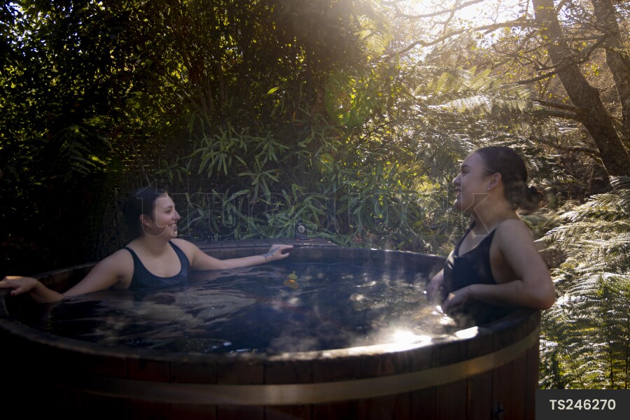 Two friends soaking in a hot tub in forest