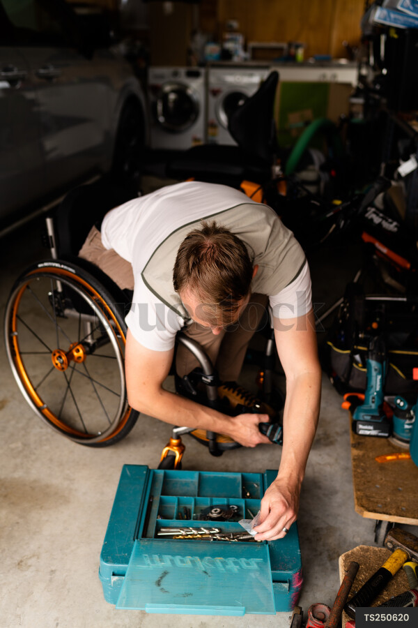 Man in wheelchair doing DIY in garage
