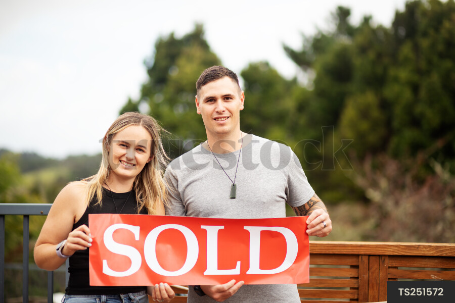 Couple with sold sign on deck