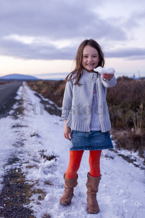 Smiling girl holding snow on road