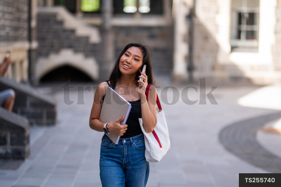 Smiling student with smartphone and book at university