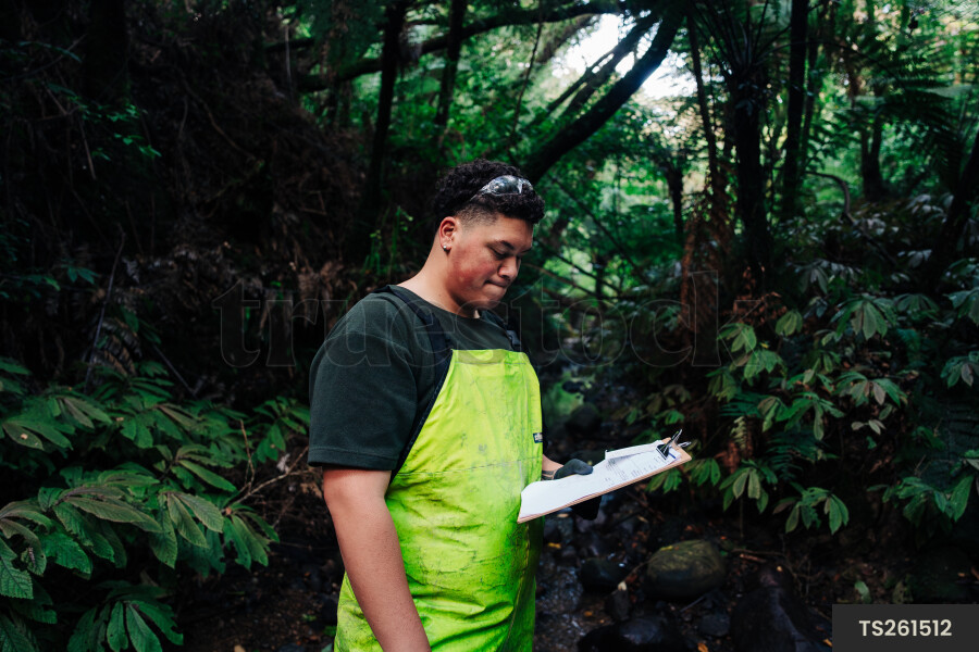 Young man looking at clipboard in forest
