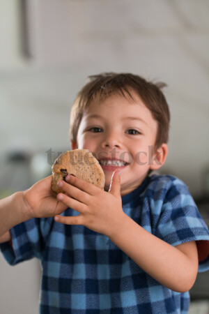 Boy holding hot cross bun and smiling