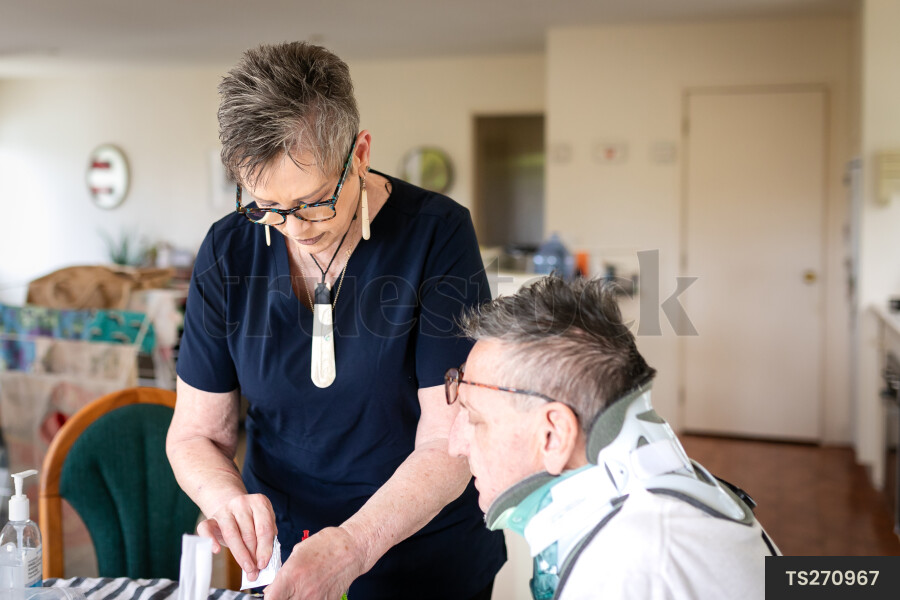 Health carer giving medicine to patient with neck brace