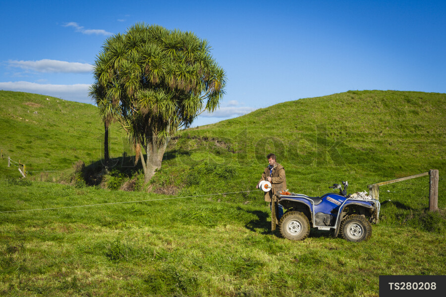 Farmer with ATV and fencing wire in field
