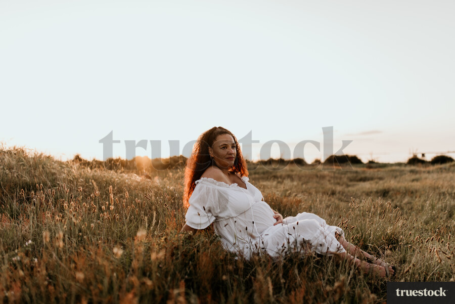 Woman Sitting in Field for Maternity Shoot
