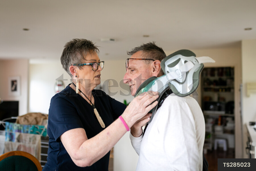 Health carer helping patient with neck brace