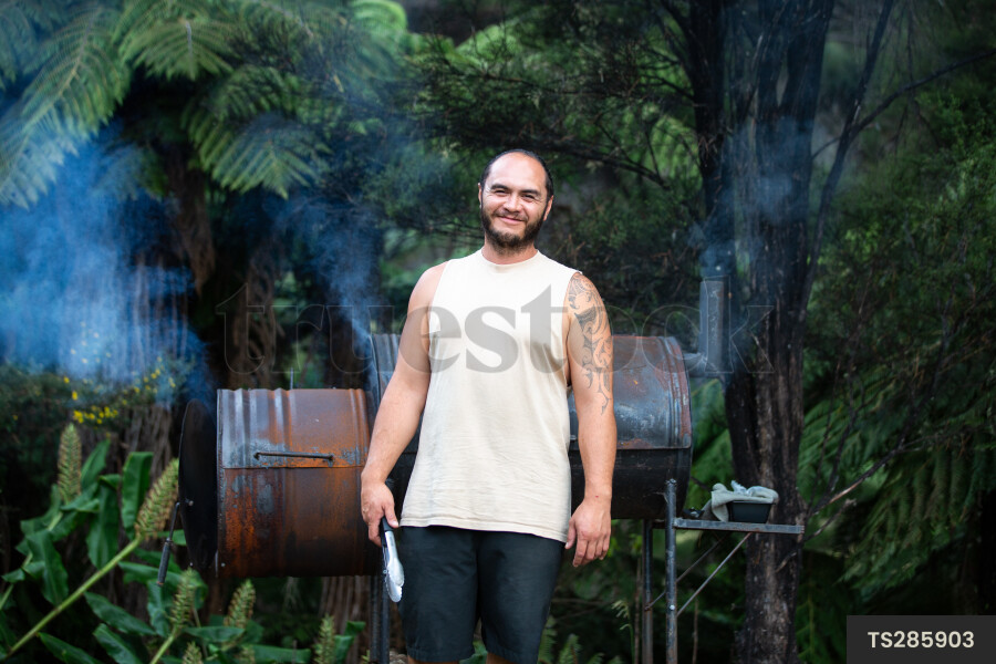 Portrait of Maori man cooking by smoker in garden