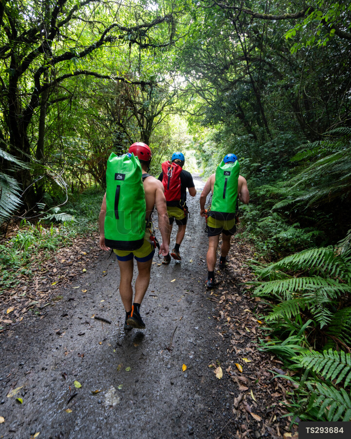 Friends hiking with dry bags on trail through forest
