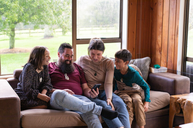 Family Using Phone on Couch