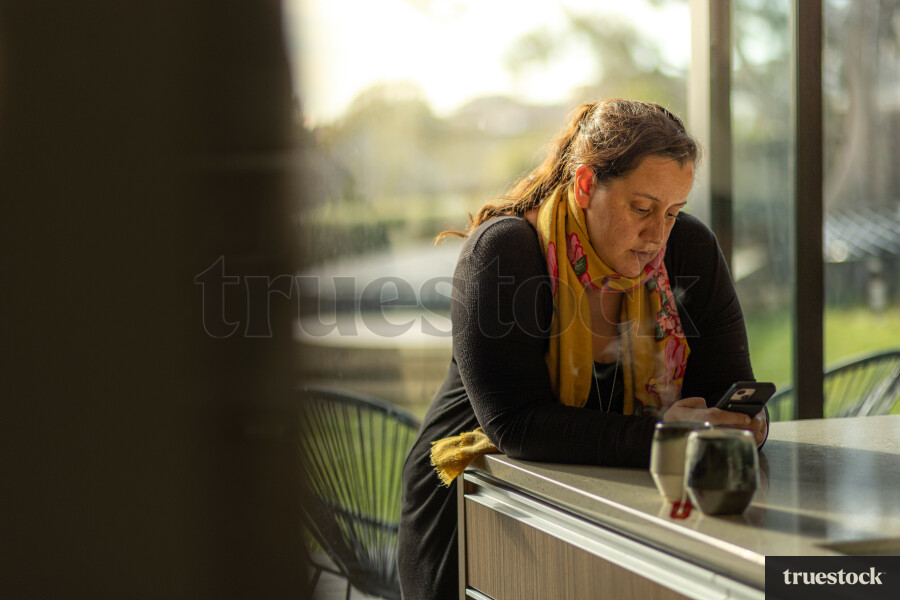 Woman Leaning Against a Counter on her Phone