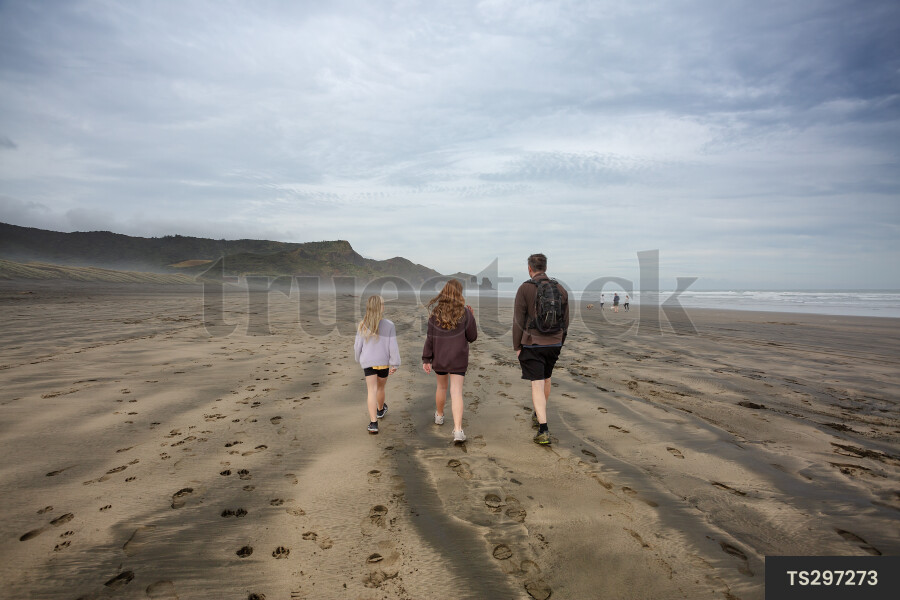 Father and daughters walking on beach