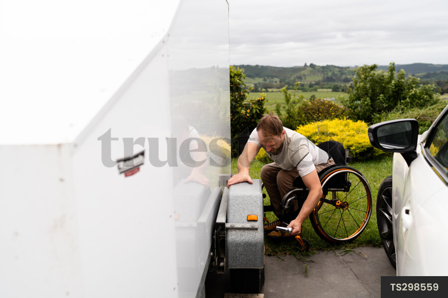Man in wheelchair changing tyre on trailer