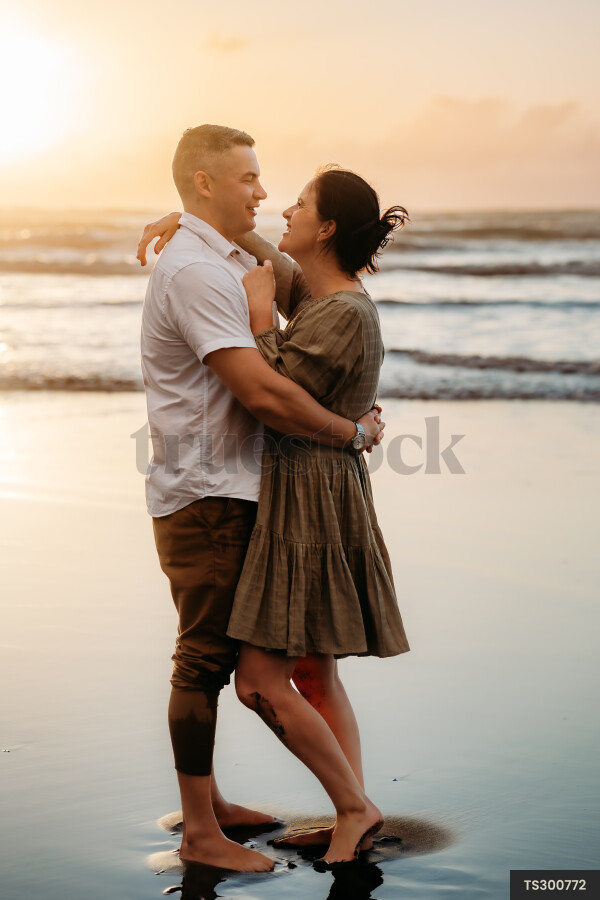 Couple embracing on beach during sunset