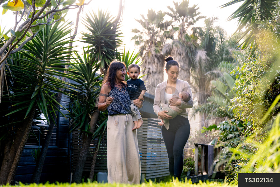 Family smiling while carrying children in garden