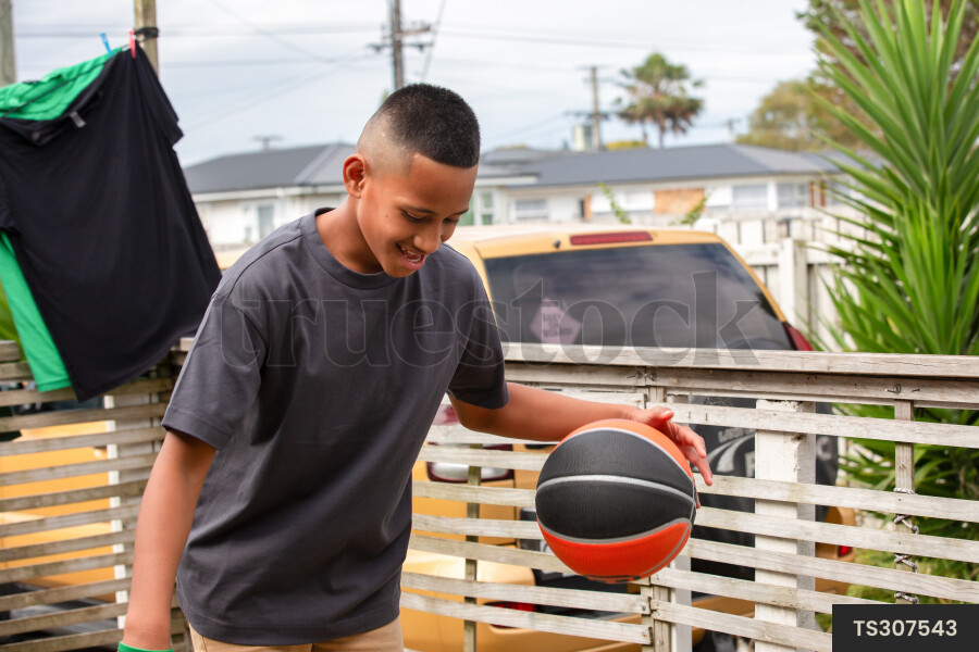 Happy togan boy bouncing basketball outside