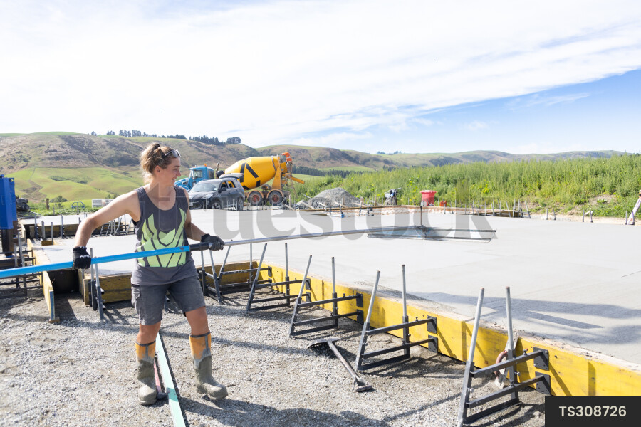Female construction worker with tool by foundation