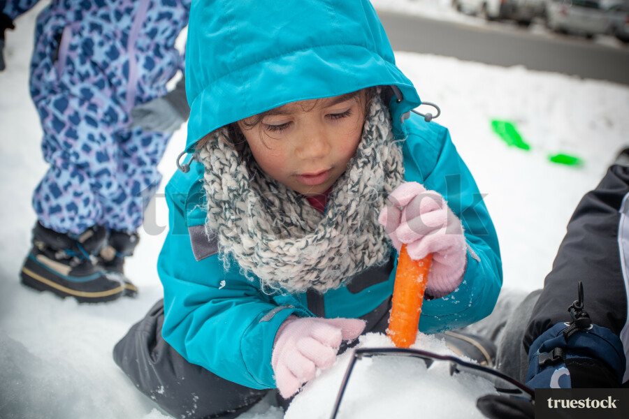 Child building a snowman in winter at the snow