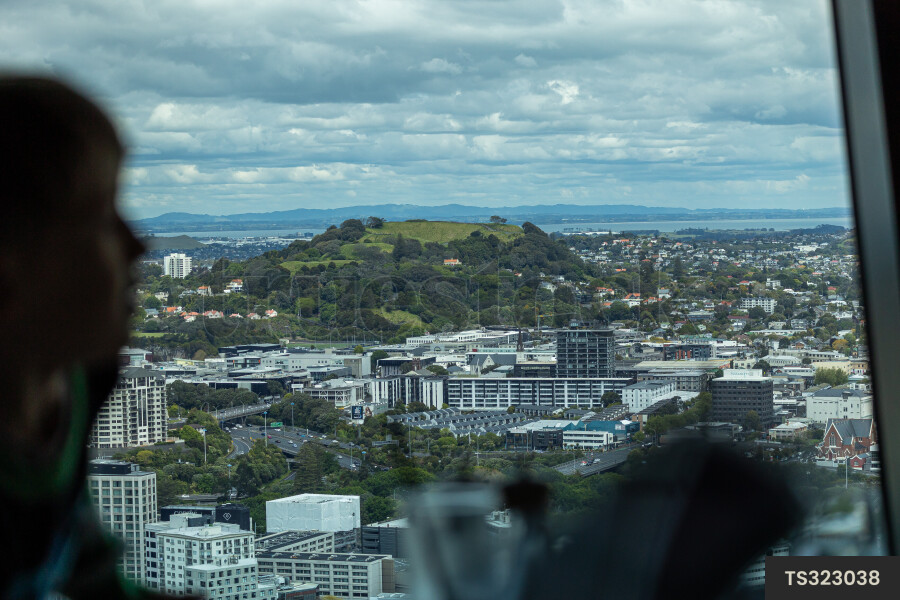 Boy by window of Sky Tower overlooking Mount Eden