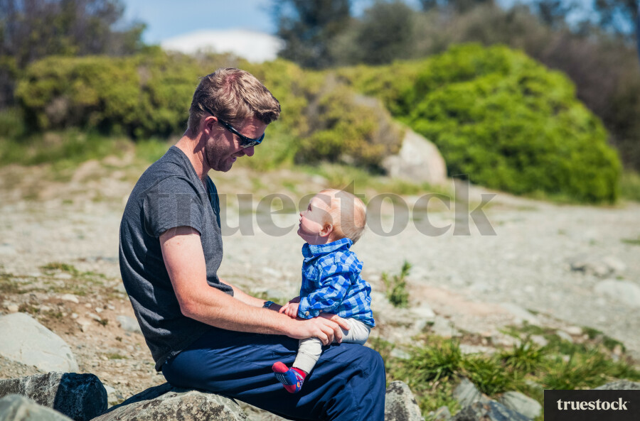 Toddler sitting on Dad's lap at the beach