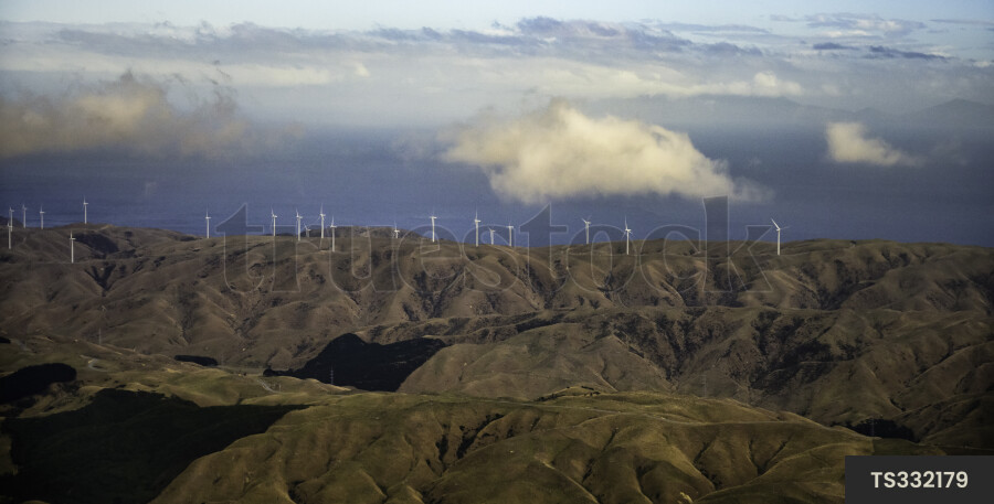 Wind turbines on mountainous landscape under clouds
