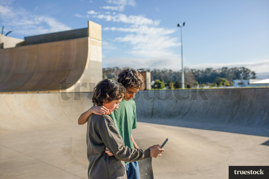 Brothers Using Phone in Skate Park