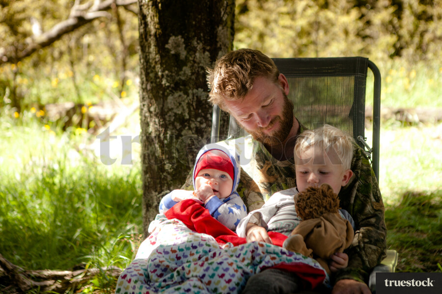 Father sitting in a camp chair with children on his lap at the campsite