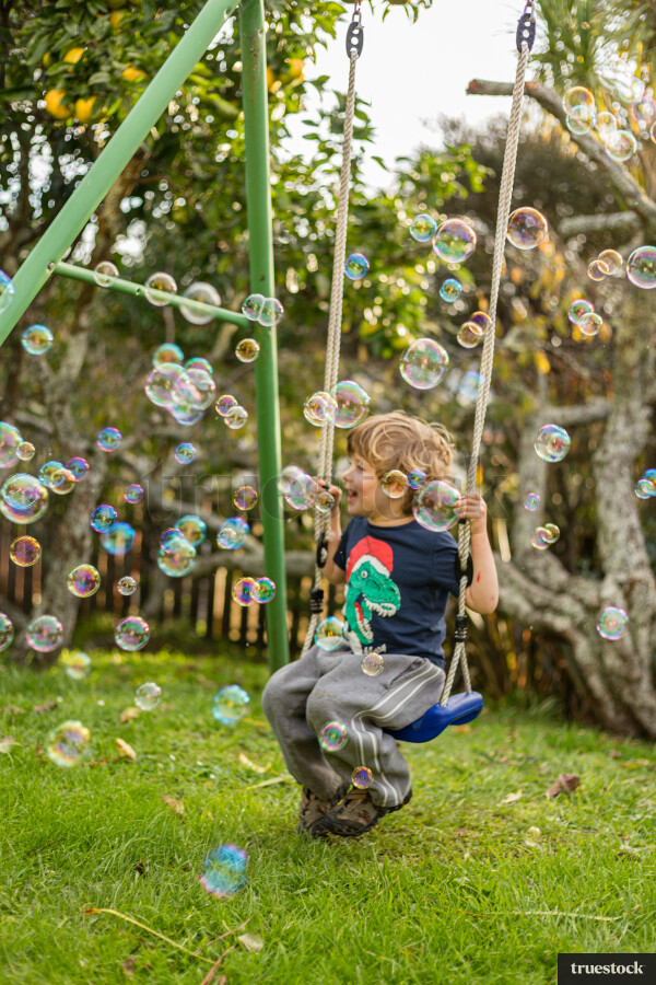 Child on the swing playing with bubbles