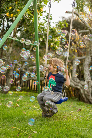 Child on the swing playing with bubbles