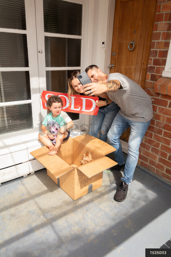 Family taking selfie with sold sign