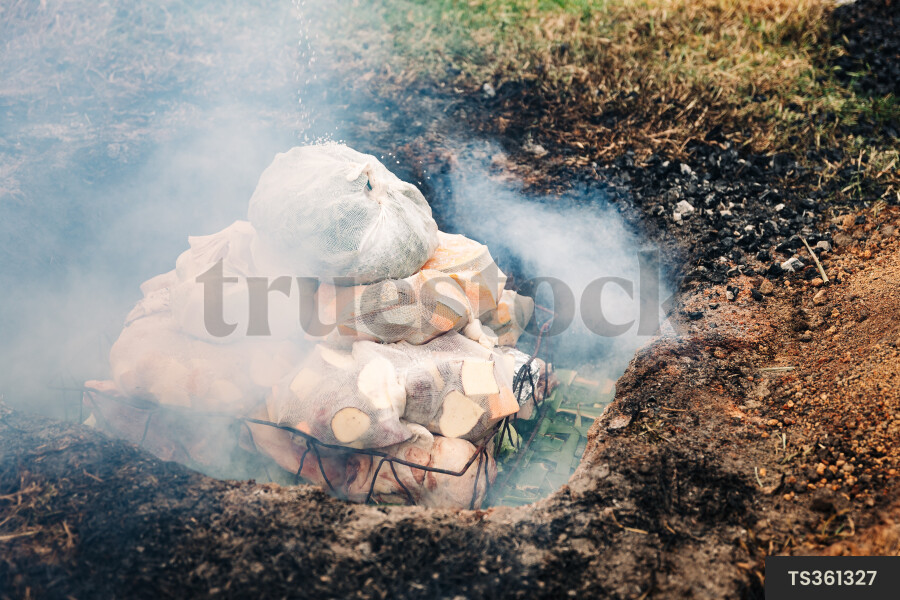 Food in grill basket cooking in traditional hangi
