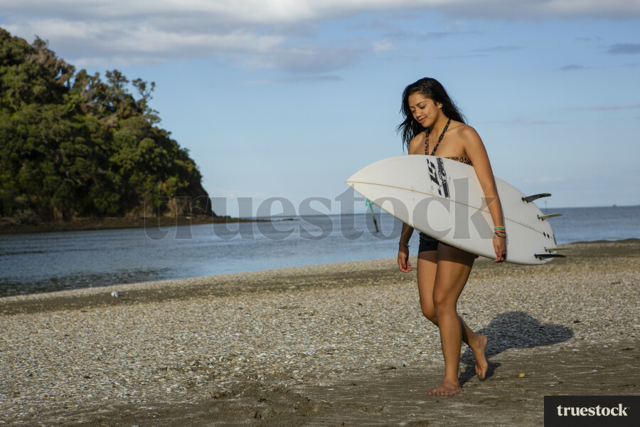 Young woman walking with surfboard