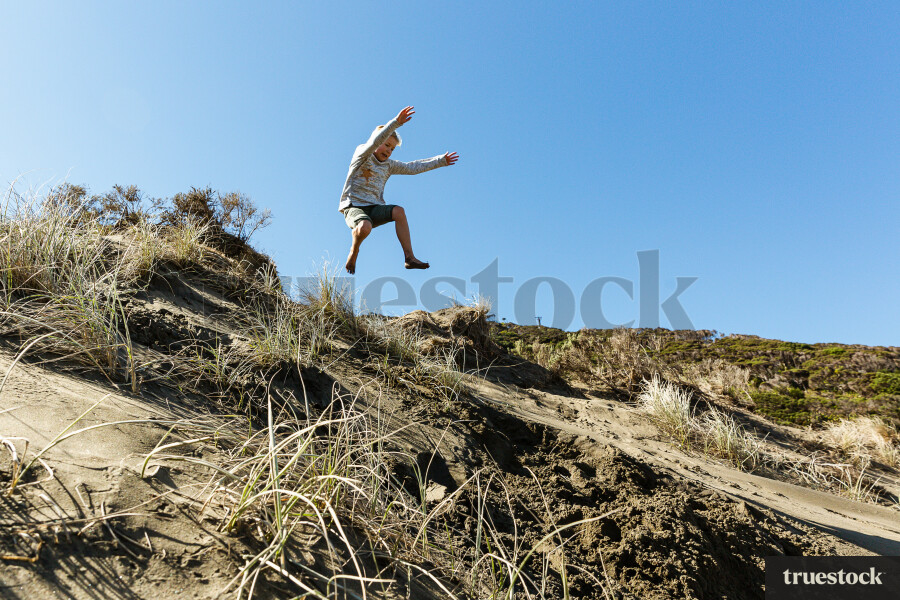 Young Kid Jumping off Sand Hill